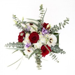 As a Bickley florist, I would call this bouquet a canvas of harmony and heritage, reminiscent of the calm streets and beloved greenspaces near Bickley station and Chislehurst Common. The composition revolves around lush, spiralling red roses-each petal a testament to enduring affection-framed by broad-faced, creamy-white gerberas with centers the hue of roasted coffee. Wisps of lisianthus, some a gentle lilac, others barely opening, meander gracefully throughout, adding a touch of whimsy and the promise of renewal. Delicate white filler flowers are nestled carefully, creating an airy buffer and a soft, cloudlike ambiance. Silvery eucalyptus leaves, distinctive for their shape and cool aroma, dance lightly above the other elements, infusing the bouquet with a sense of motion and woodland freshness familiar to those who stroll through Jubilee Country Park. Strong, sleek leaves curl around the base, securing the bouquet's elegant form and giving it a contemporary edge. The clear glass vase allows the natural beauty and verdant vitality of each stem to shine through, symbolising purity and craftsmanship. Whether to mark a special day, send heartfelt wishes, or simply adorn a Bickley table, this arrangement expresses local artistry, seasonal abundance, and the subtle sophistication of a well-composed floral statement.