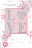 This softly romantic anniversary card appears as though it has been lovingly set aside with a bouquet ready for delivery somewhere along Bickley's quiet avenues. The design is anchored by the word LOVE, its letters raised and edged with a delicate dusting of glitter that catches the light in tones of blush pink and silver. The texture of the lettering adds a subtle tactile charm, encouraging the recipient to trace the contours with their fingertips. Behind and around this central word lies a gentle wash of blush pink, forming a slightly deeper panel that sets LOVE apart from the rest of the card. From this panel, clusters of stylised blossoms and slender vines extend in graceful arcs, their forms drawn in fine, flowing lines that mimic the light touch of a florist sketching an anniversary design. The flowers are shaded in pastel pinks, soft mauves, creamy whites, and gentle greys, with occasional hints of silvery detailing that reflect ambient light, much like petals catching daylight in a Bickley bay window. Tiny butterflies, curls, and petal-like motifs punctuate the spaces between the larger blooms, giving the impression of subtle motion and airiness. The accompanying text-phrases such as On Our Anniversary and I love you today and always-is rendered in elegant, handwritten-style script, its looping strokes echoing the swirling stems and foliage. Overall, the card conveys a sense of treasured intimacy and calm celebration, its pastel palette, glimmering accents, and floral motifs working together to express enduring love. It feels perfectly suited to accompany a hand-tied anniversary bouquet in Bickley, capturing the tenderness of long-term commitment in both words and design.